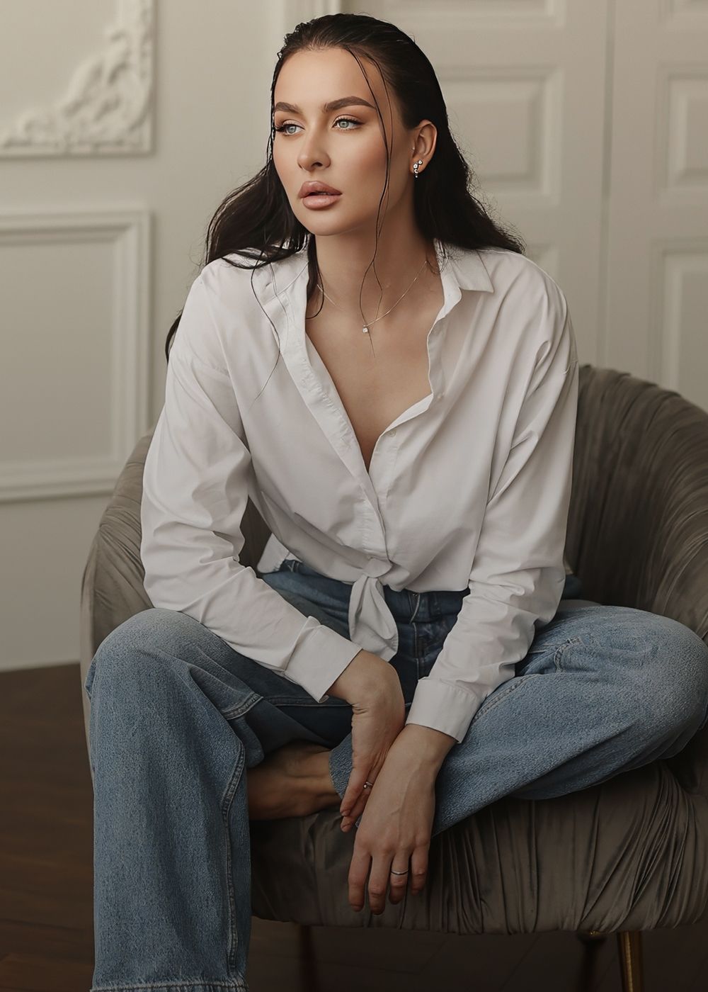 Woman in white shirt and denim jeans sitting.