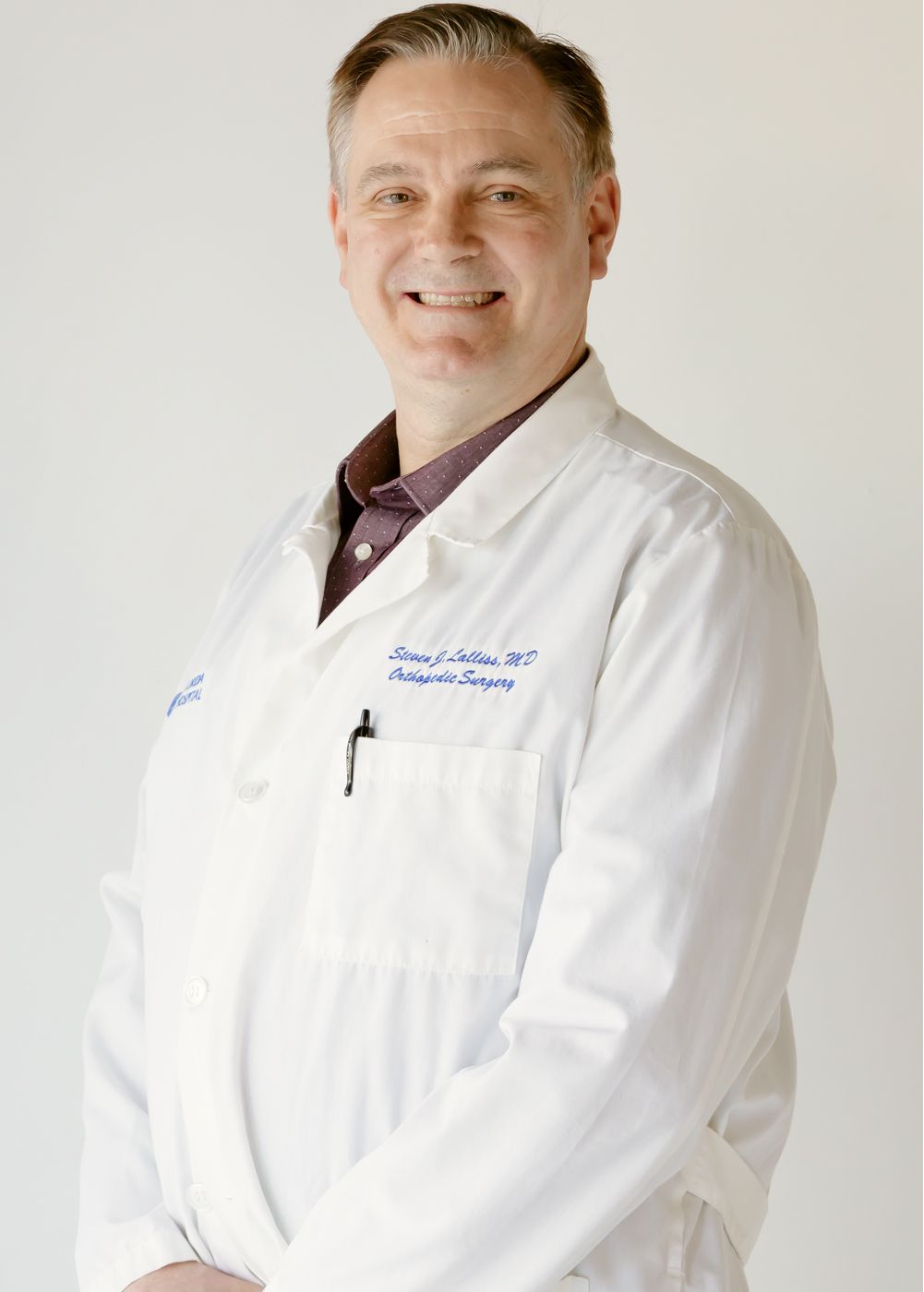Female doctor in white coat, smiling confidently.