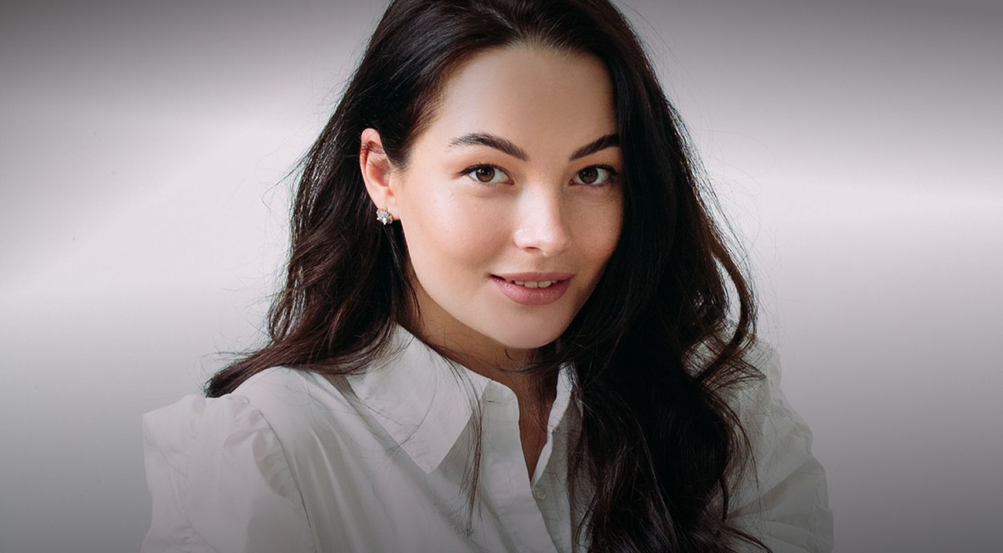 Smiling woman with long dark hair in white shirt.