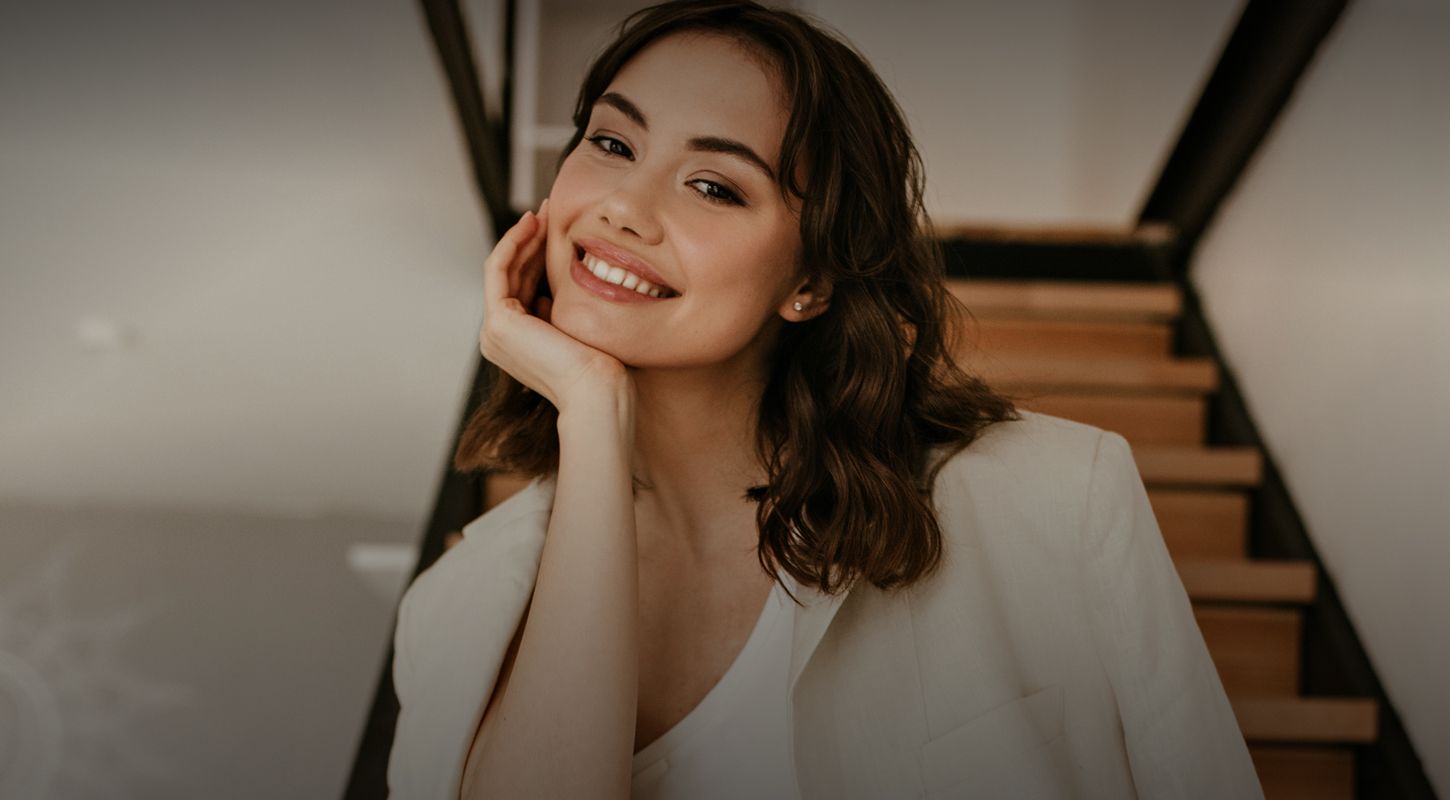 Smiling woman resting chin on hand indoors.
